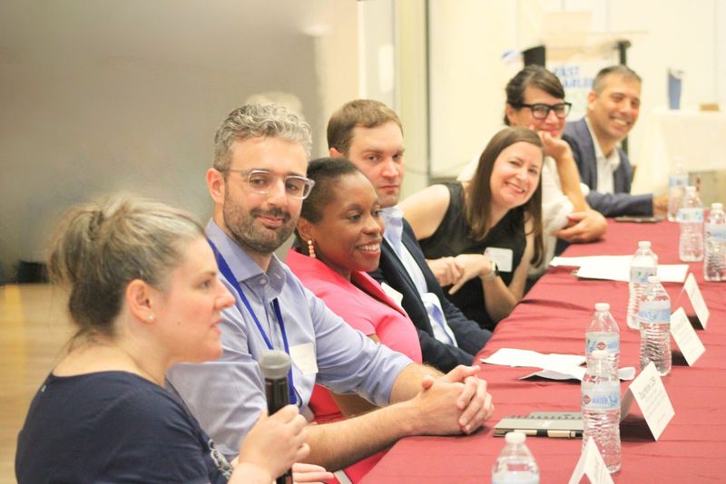 Panelists smiling and speaking into a microphone during a discussion at the 2025 Street Psychiatry Conference.